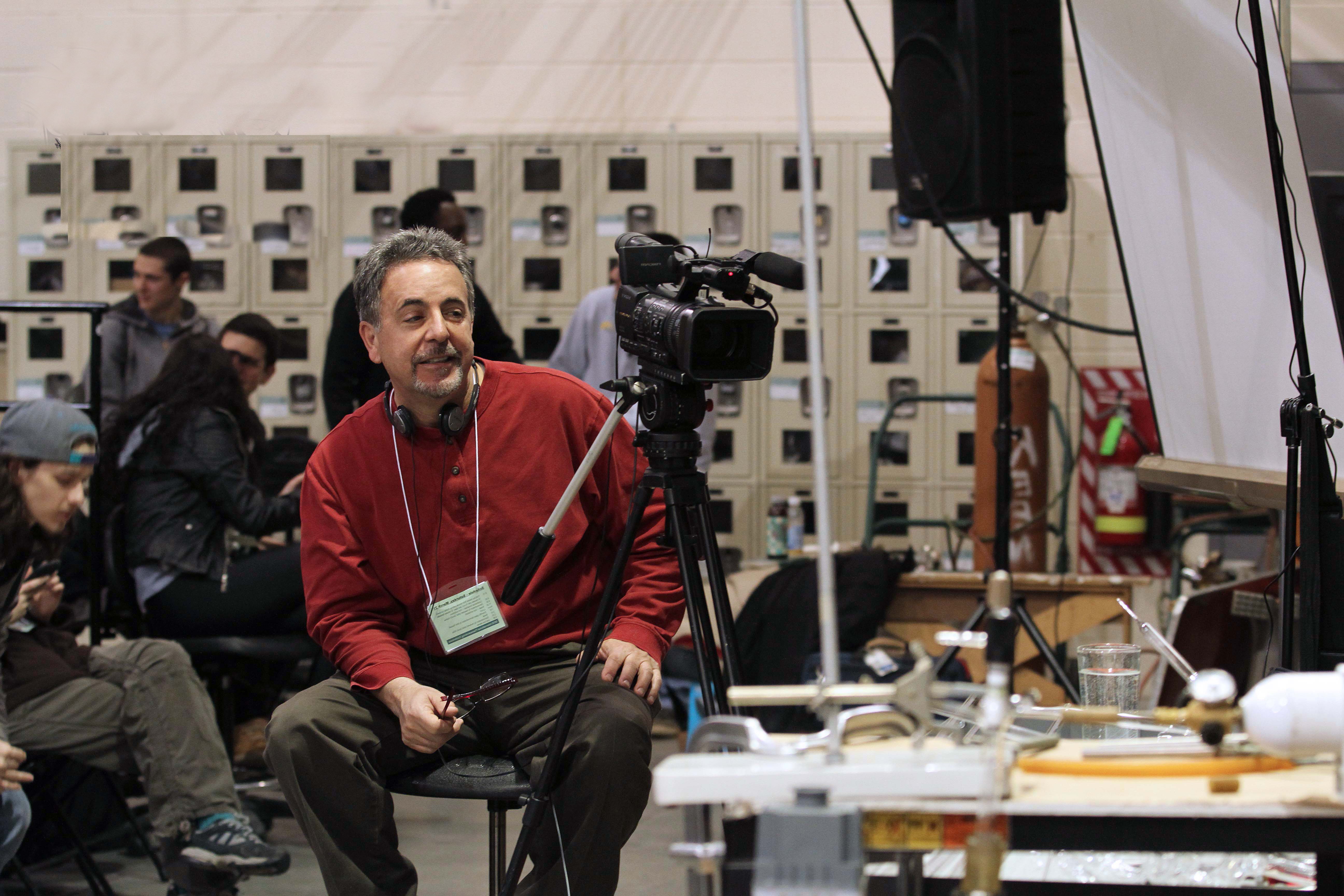 Tommy sitting beside a camera on a tripod at Salem Community College