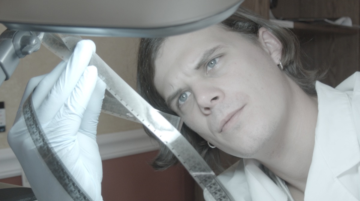 Technician in white gloves inspecting a strip of film