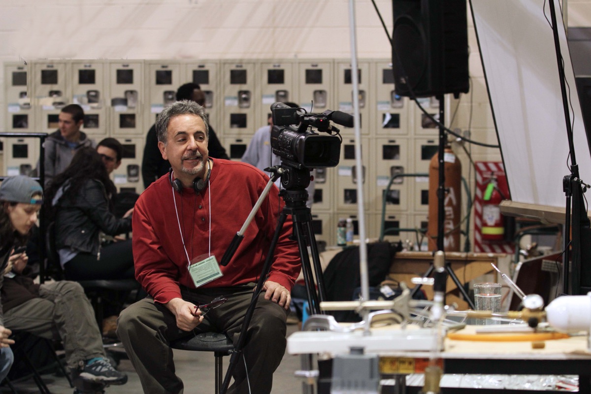 Tommy sitting beside a camera on a tripod at Salem Community College